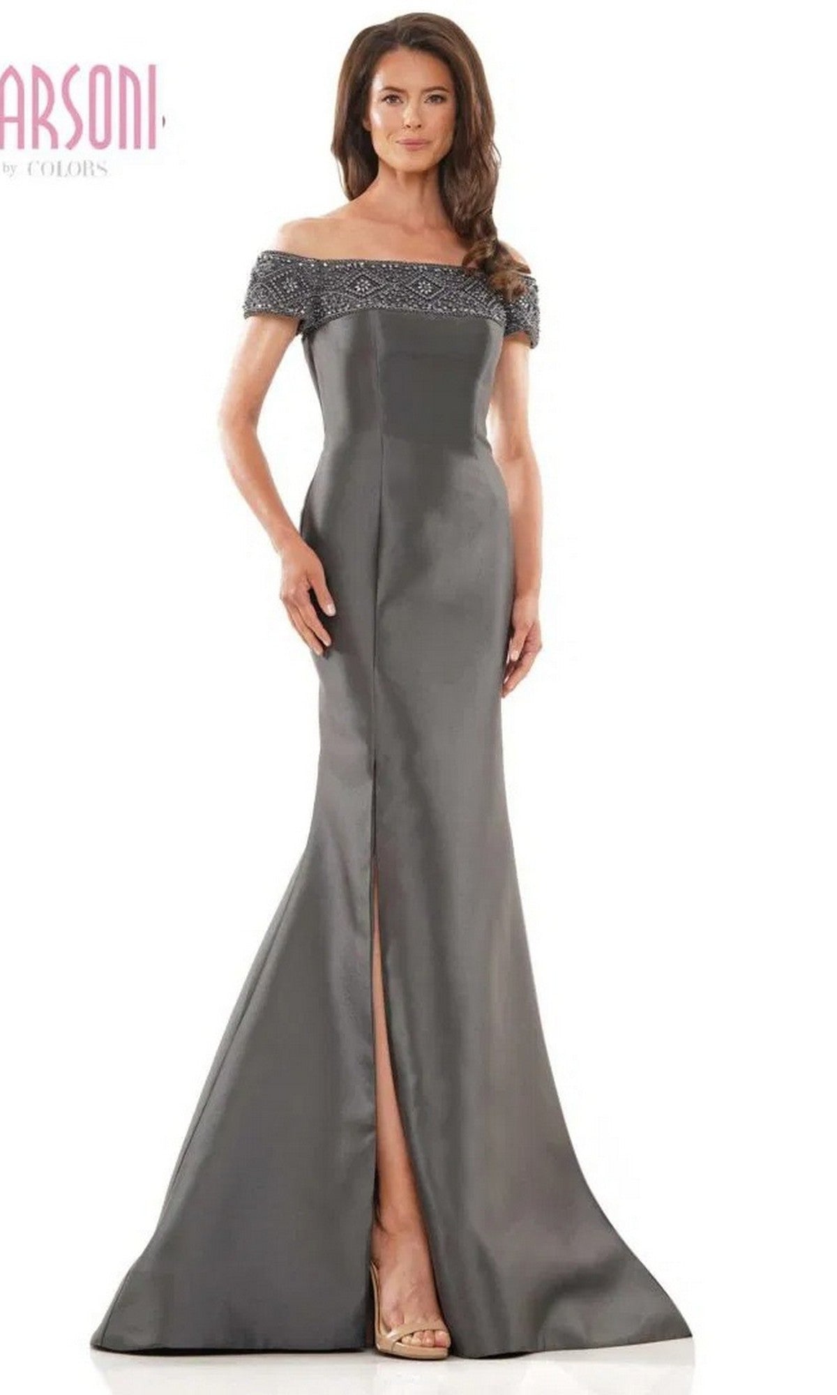 A woman poses in the Marsoni MV1184 Long Formal Dress, showcasing its charcoal hue, off-shoulder neckline, beaded details, mermaid skirt, and front slit against a plain white background.